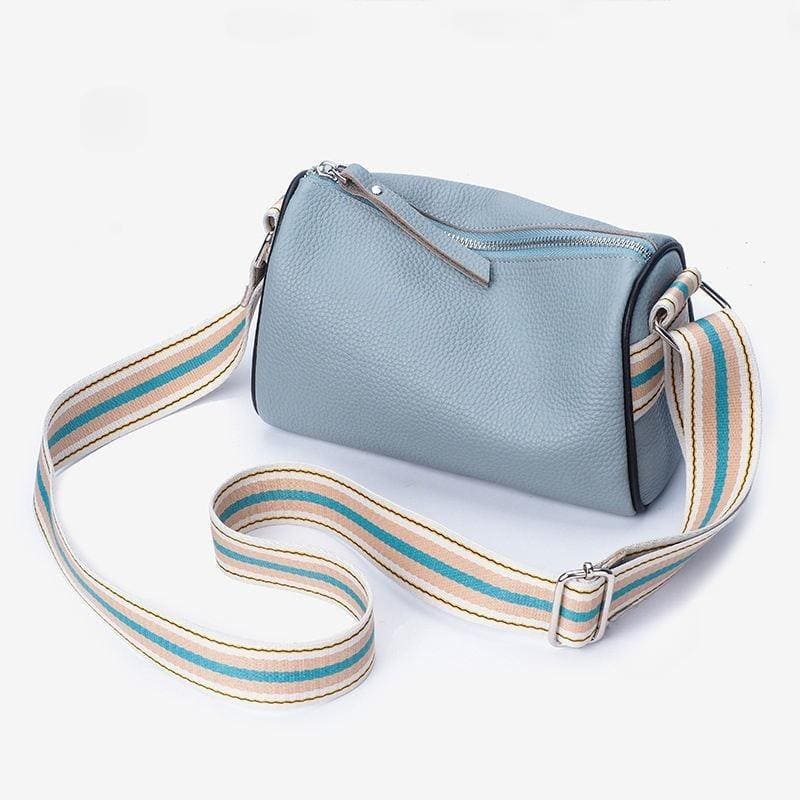 Light blue textured leather crossbody bag with adjustable striped strap, ideal for daily use and fashion accessories. Perfect for women seeking a fashionable and functional handbag.