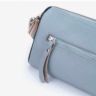 Blue leather crossbody bag with silver zipper and adjustable strap, perfect for casual and formal wear.