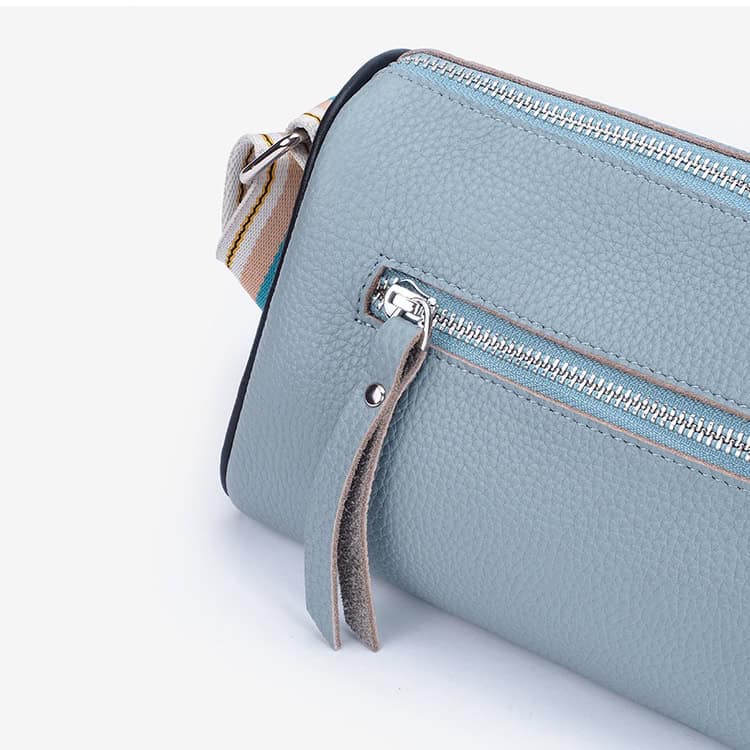 Blue leather crossbody bag with silver zipper and adjustable strap, perfect for casual and formal wear.