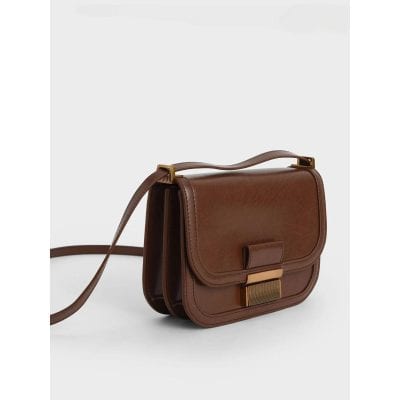 Elegant brown leather optical bag perfect for women, featuring a secure flap closure and adjustable strap, ideal for carrying glasses, sunglasses, or small essentials with style.