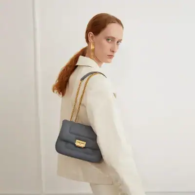 Stylish gray handbag featuring a gold turn-lock closure, perfect for fashion-forward accessories.