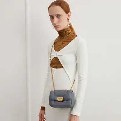 Elegant grey leather purse with gold chain and clasp, perfect for stylish outfits and everyday wear.