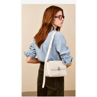 Elegant white handbag layered over a casual light blue shirt and black jeans, perfect for fashion-forward woman.