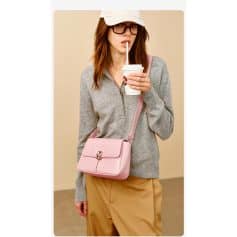 Fashionable woman with pink leather handbag, gray zip-up sweater, drinking coffee, casual style at Monalisa Medical Store.