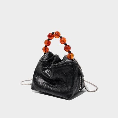 Stylish black leather handbag featuring a unique amber bead handle, perfect for fashion-forward accessories. Ideal for elegant outings or casual chic looks.