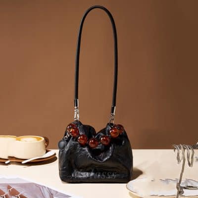 Stylish black handbag from Monalisa Store featuring a unique amber bead handle for a chic look. Perfect for casual or formal outfits, adding elegance to your wardrobe.