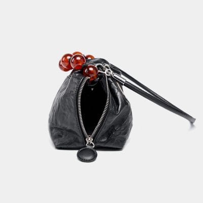 Stylish black leather eyewear case with zipper closure and red beaded handle, perfect for storing sunglasses and glasses, combining fashion and functionality.