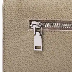 Close-up of a beige leather bag featuring a sleek silver zipper and locking system, emphasizing style and security for accessories or personal items.