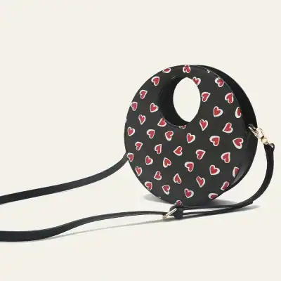 Stylish black circular purse featuring red and white heart designs, perfect for casual or date night outfits.