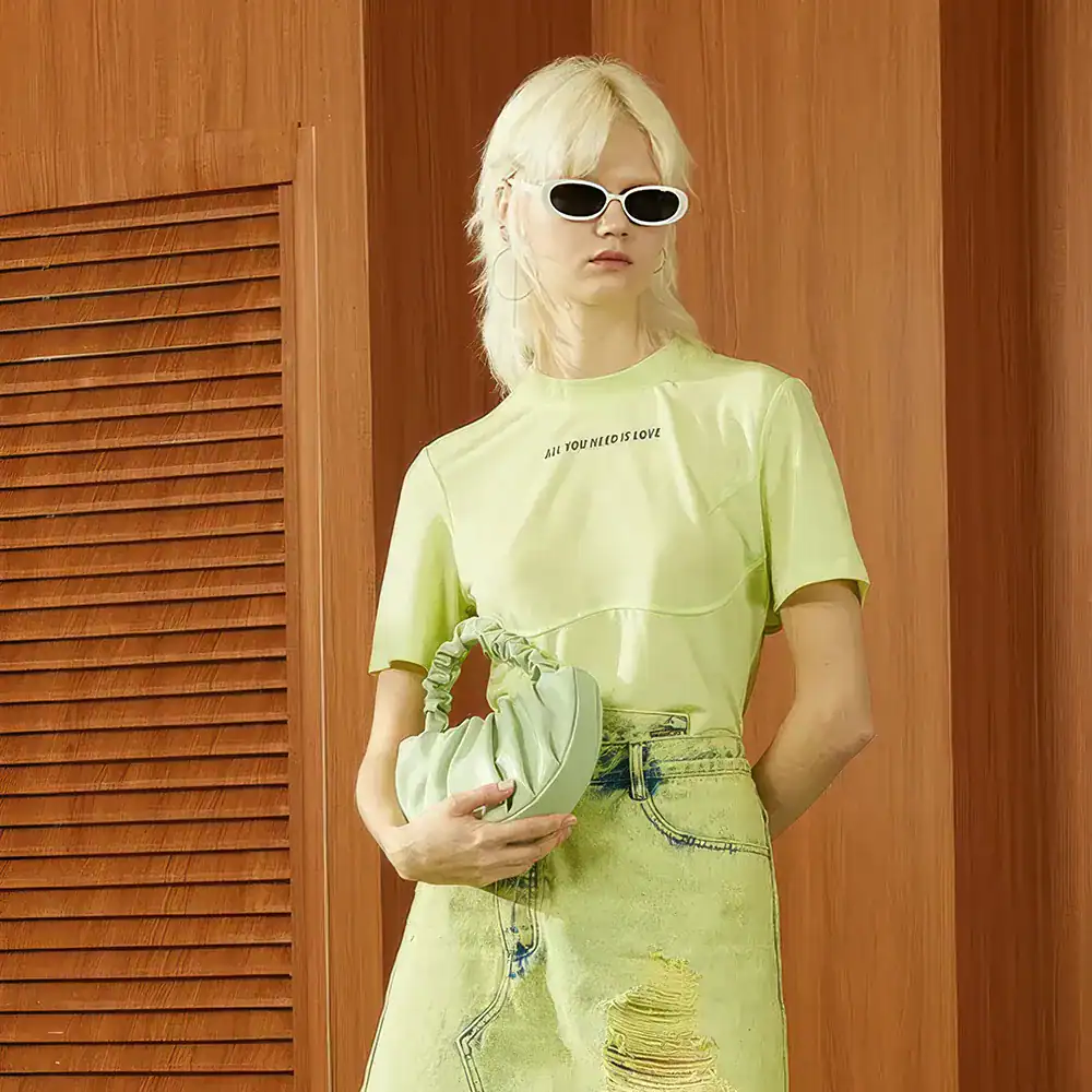 Stylish blonde woman wearing bold sunglasses and a yellow outfit at Monalisa Store, emphasizing contemporary eyewear and optic fashion.