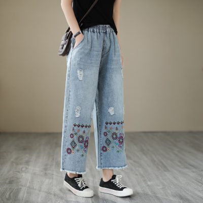 High-waisted distressed wide-leg jeans with colorful embroidery, casual streetwear style, perfect for fashion-forward outfits.