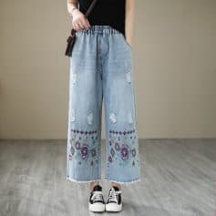 Comfortable distressed denim with colorful embroidery detail on hem, perfect for trendy casual wear. Features ripped accents, relaxed fit, and versatile style suitable for various outfits.