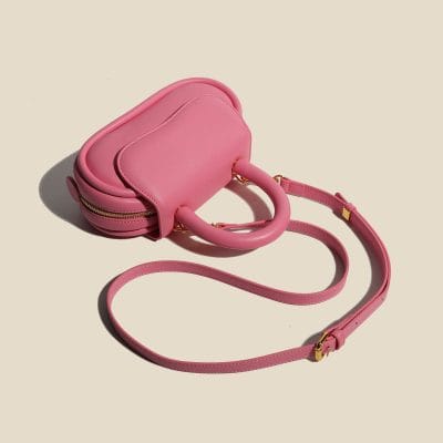 Stylish pink eye care accessory bag with handle and adjustable strap, perfect for storing glasses, contact lens supplies, or eye care essentials, combining fashion and functionality.