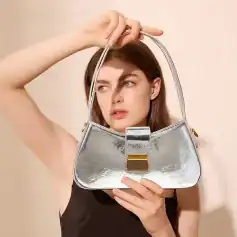 A fashionable woman holding a metallic silver handbag with a gold accent, showcasing trendy accessories for women.
