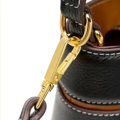 Adjustable gold clasp with brown leather details on high-end leather bag. Ideal for stylish accessories and luxury brands.