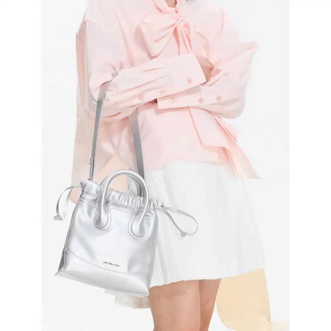 Elegant pink blouse with bow detail paired with a modern white handbag for women’s fashion and accessories.