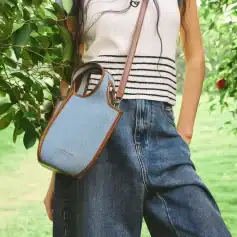 Stylish blue canvas crossbody bag with brown leather accents, perfect for everyday use and fashionable outings.