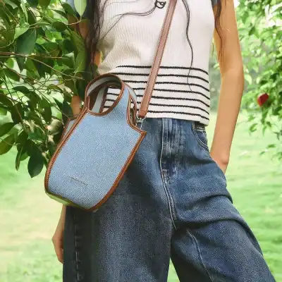 Stylish blue canvas crossbody bag with brown leather accents, perfect for everyday use and fashionable outings.