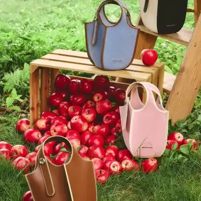 Vibrant handbags displayed outdoors with fresh apples, showcasing trendy women's bags perfect for casual and fashion-forward occasions.