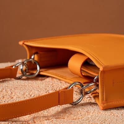 Stylish orange vegan leather handbag with silver hardware, perfect for everyday use. Lightweight and durable, ideal for women seeking eco-friendly fashion accessories.