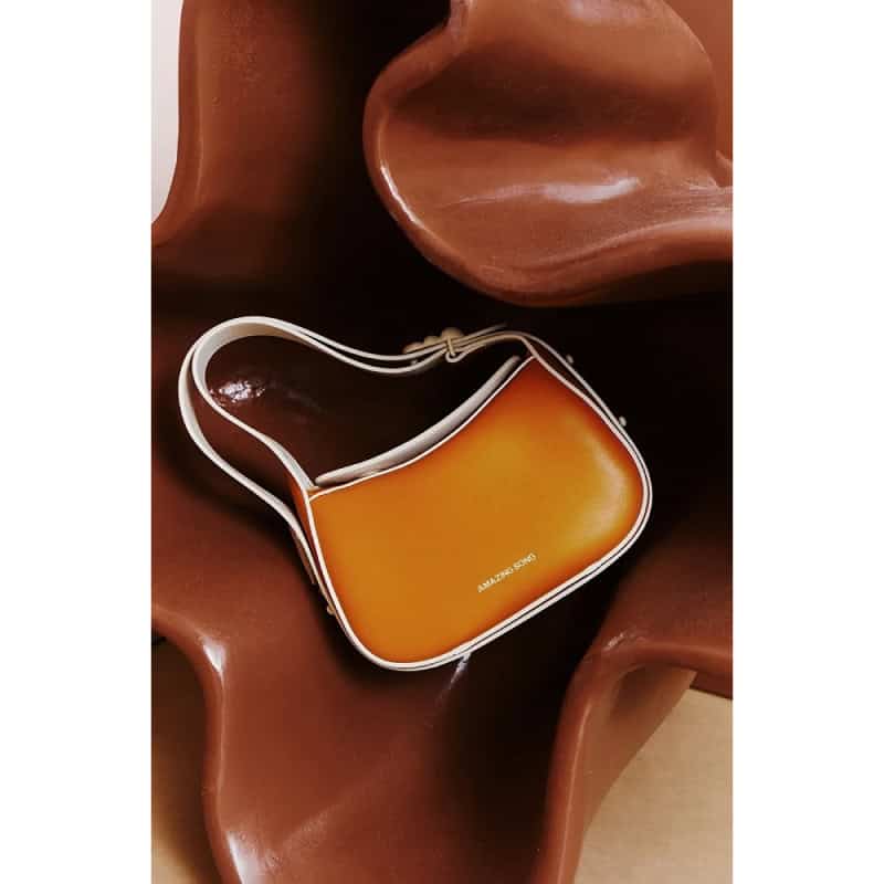 Elegant orange designer optic bag with white strap, perfect for fashion accessories and trendy eyewear storage.