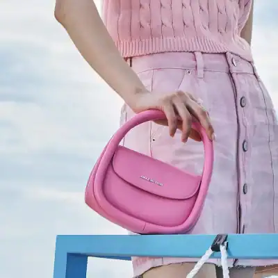A fashionable pink handbag held by a woman dressed in pink, perfect for chic casual outings and adding a pop of color to any outfit.