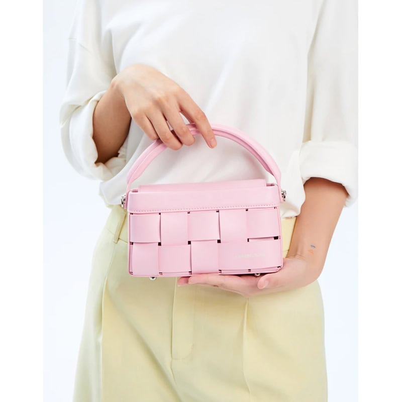 Pink designer handbag with woven strap detail, perfect for fashion-forward accessories. Ideal for casual or formal occasions, available at Monalisa Store.