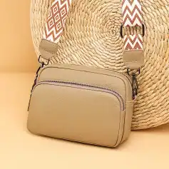 Stylish beige leather crossbody bag with zippered compartments, perfect for fashion-forward accessories and daily essentials.