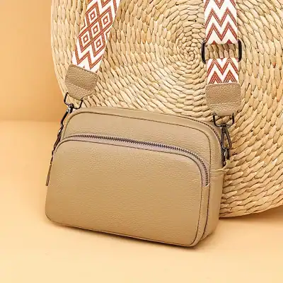 Stylish beige leather crossbody bag with zippered compartments, perfect for fashion-forward accessories and daily essentials.