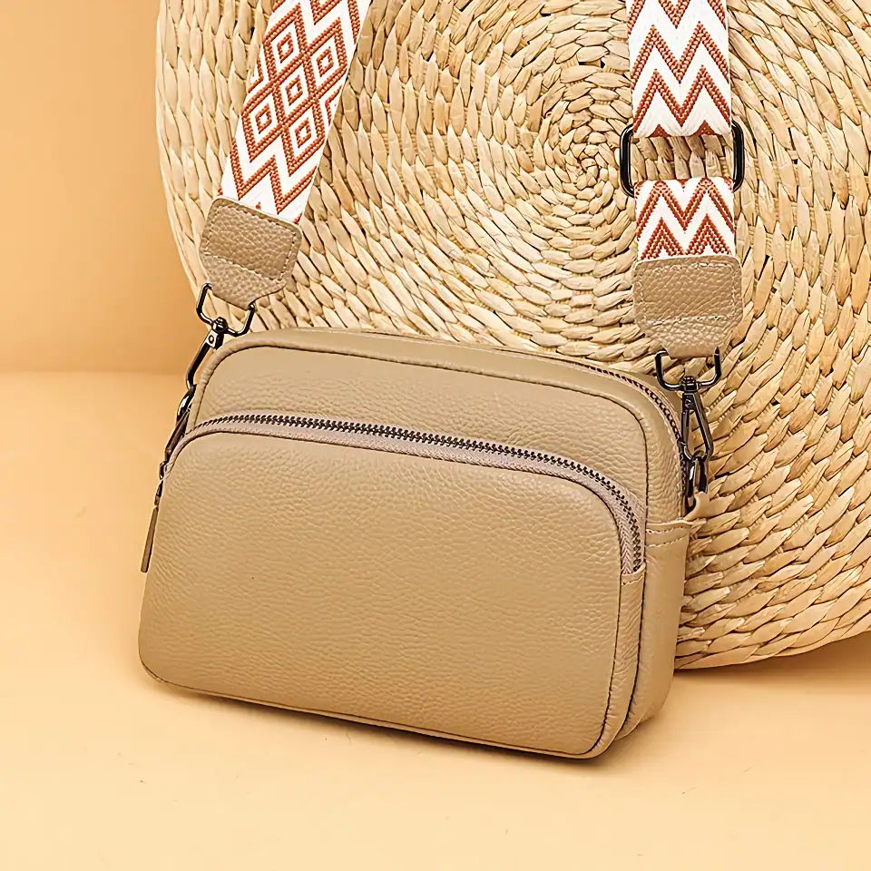 Stylish beige leather crossbody bag with zippered compartments, perfect for fashion-forward accessories and daily essentials.