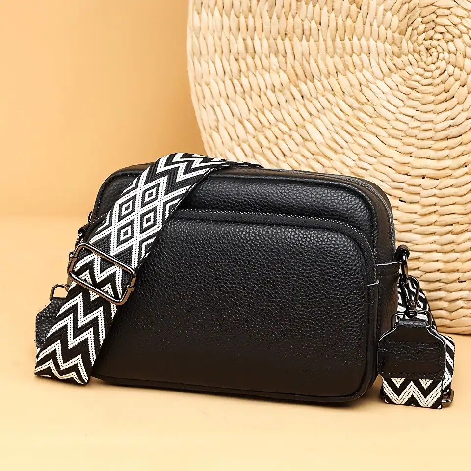 Stylish black leather crossbody bag featuring a trendy black and white zigzag strap, perfect for everyday use and showcasing modern fashion and functionality.