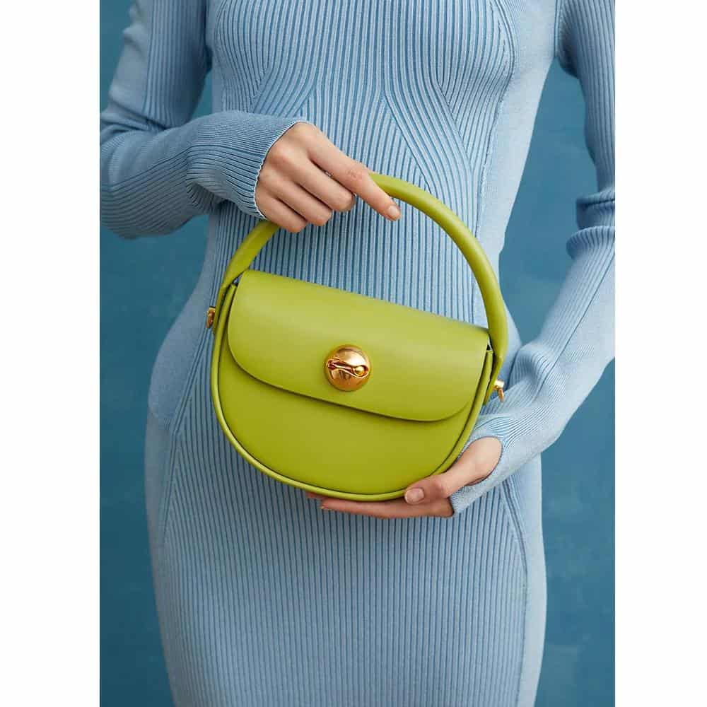 Bright green fashion handbag with a rounded design, featuring a gold twist lock closure and a sleek top handle, perfect for stylish accessories.