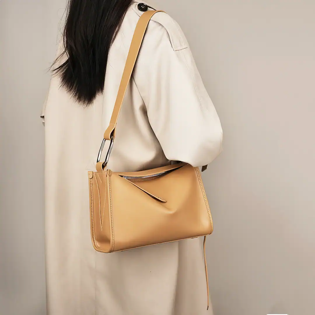 Stylish beige leather shoulder bag featured on woman wearing a cream-colored trench coat, perfect for professional or casual occasions, highlighting trendy women's accessories.