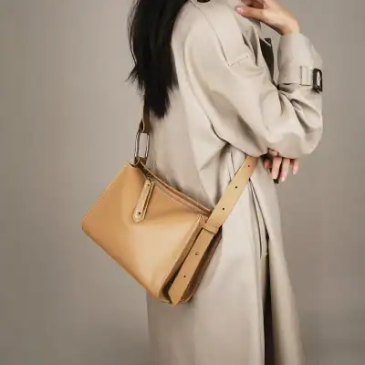 Elegant beige crossbody bag with adjustable strap, zipper compartment, ideal for stylish and practical accessories.