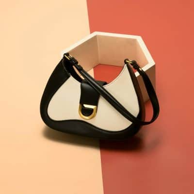 Elegant fashion handbag for women featuring black and white leather with gold accents, perfect for daily use or special occasions.