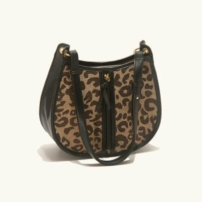 Leopard print designer handbag with black leather accents, gold hardware, and adjustable straps, perfect for fashion-forward individuals.