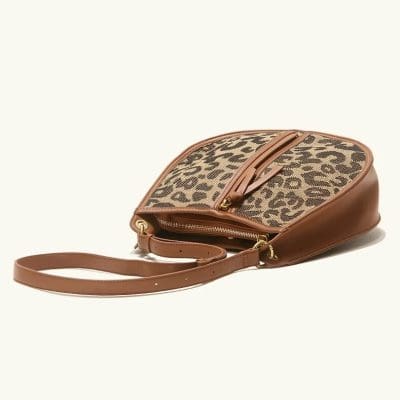 A chic brown leather bag with a leopard print fabric panel, perfect for fashion-forward individuals and accessories shoppers. Features a zippered pocket and adjustable strap for versatile wear.
