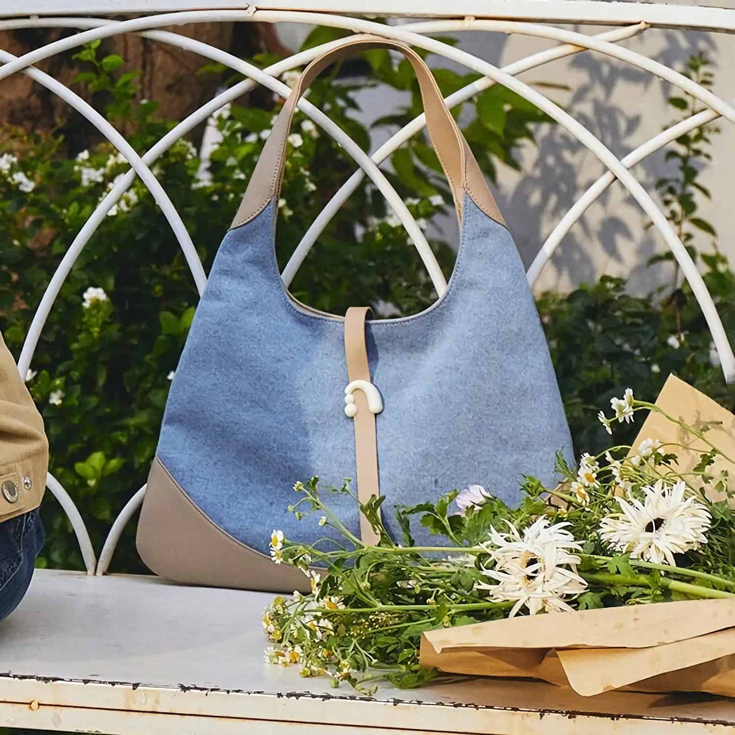 A fashionable blue tote bag from Monalisa Store featuring a beige leather handle and accents. Ideal for women seeking a versatile and trendy accessory for daily outings and shopping needs.