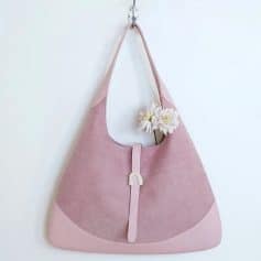 Stylish pink tote bag with a floral detail on a white background, featuring a unique rainbow-shaped clasp for a chic look, perfect for daily use.