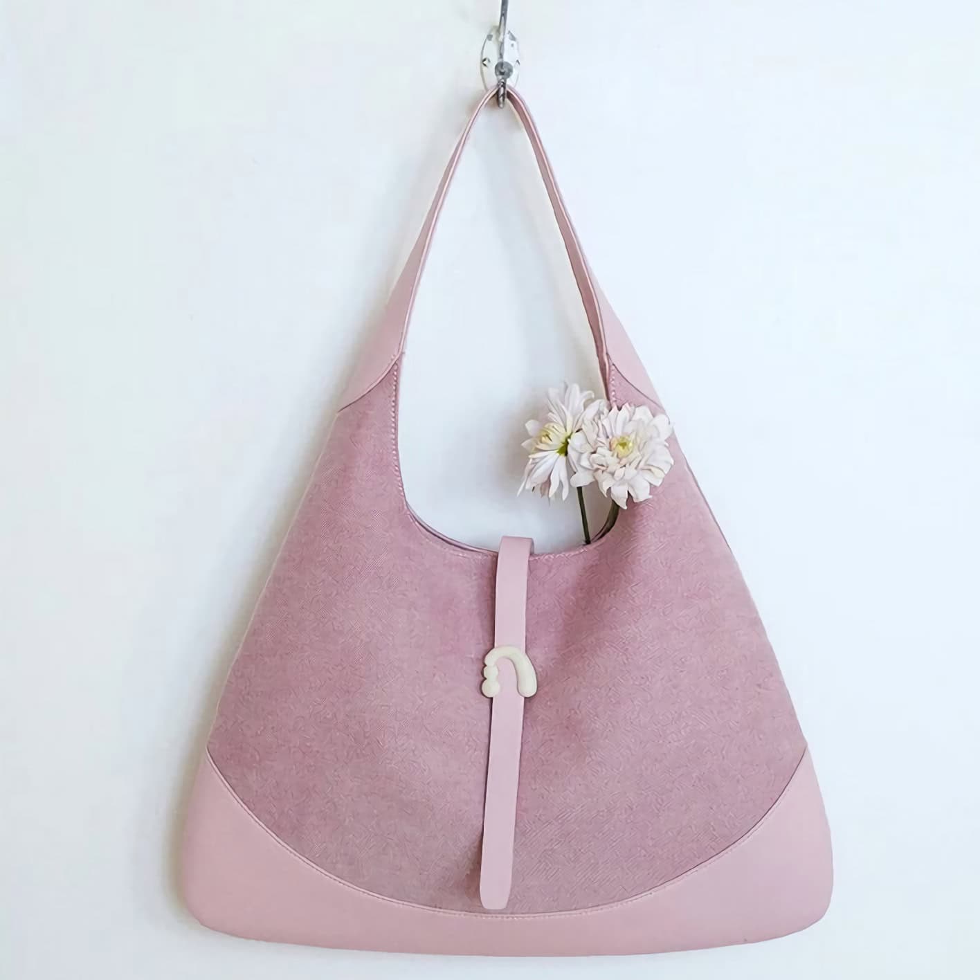 Stylish pink tote bag with a floral detail on a white background, featuring a unique rainbow-shaped clasp for a chic look, perfect for daily use.