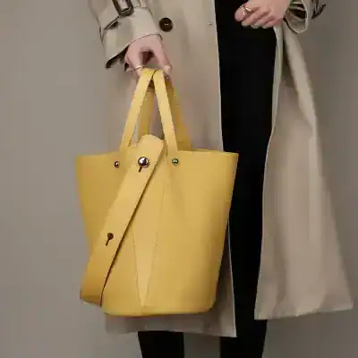 Stylish yellow leather tote bag with adjustable strap, perfect for shopping or daily use, featuring a spacious interior and durable design.