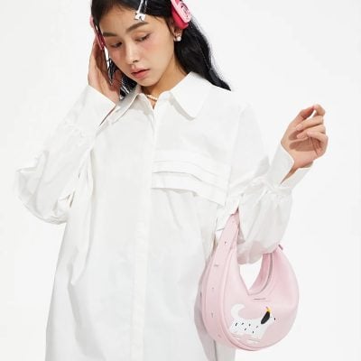 Young woman wearing stylish white blouse and playful swan-themed pink handbag, perfect for casual or chic outings, combining fashion with a touch of fun.