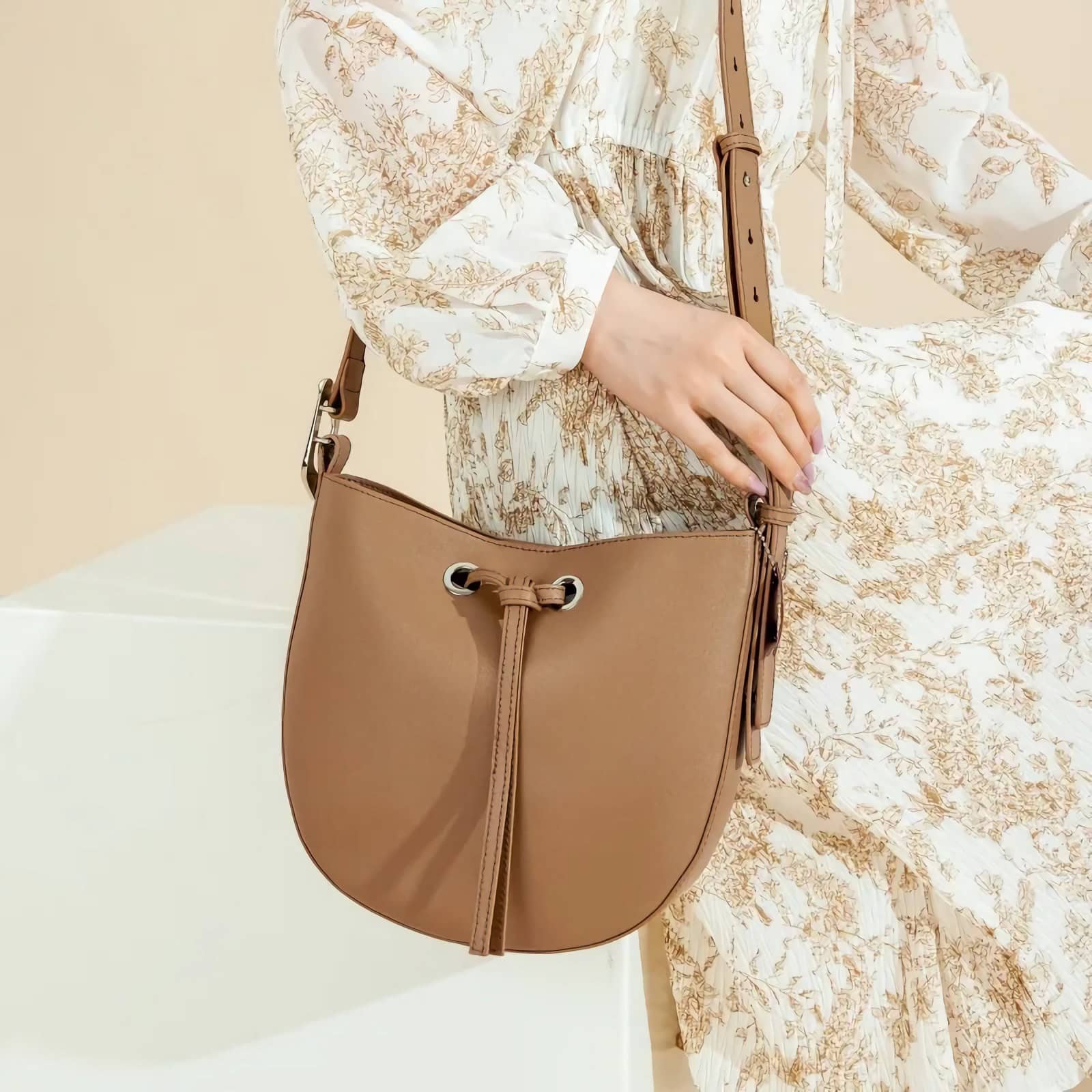 Stylish tan leather shoulder bag with adjustable strap and drawstring closure, perfect for casual and everyday use.
