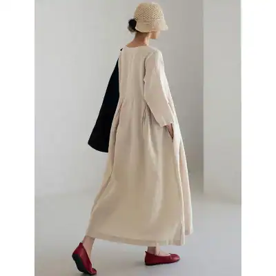 Photo of a woman modeling a stylish beige maxi dress with long sleeves and a flowing silhouette, perfect for casual or semi-formal occasions.