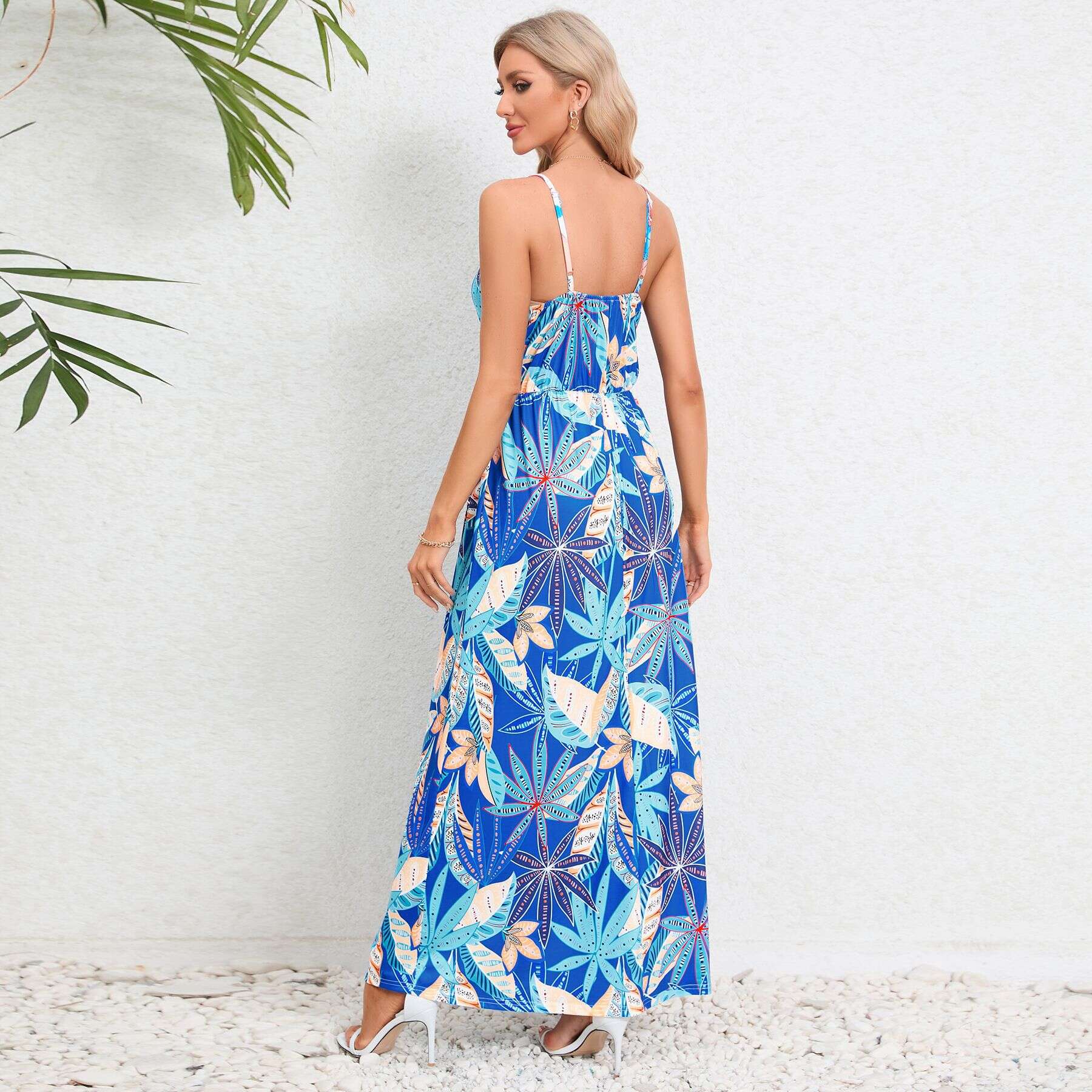 Bright blue maxi dress featuring a tropical leaf motif, adjustable spaghetti straps, and a flowy silhouette perfect for warm weather and beach vacations.
