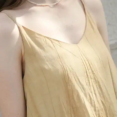 Close-up of a sleeveless, silk-like beige dress emphasizing smooth texture and elegant style, ideal for skincare or beauty store displays.