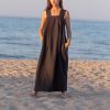 Stylish long linen dress for women on the beach with ocean backdrop.