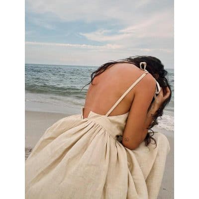 Elegant beige dress with thin straps on the beach for summer fashion and style. Perfect for seaside outings, beach vacations, and trendy resort wear.