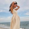 Elegant woman in sundress by the ocean, showcasing stylish beachwear perfect for summer, vacation, and seaside occasions.